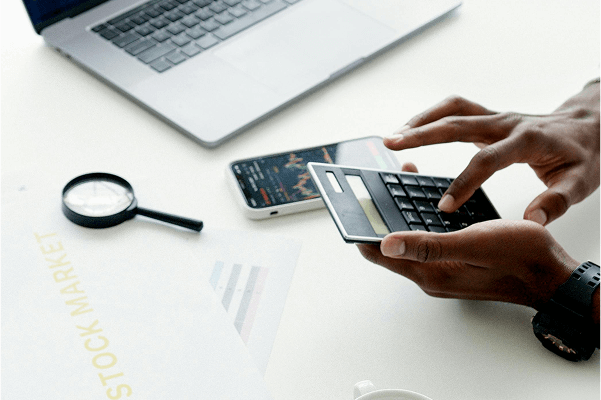 ภาพแสดงบุคคลกำลังฝึกคำนวณและวางแผนการเทรด - Ultima Markets